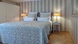 A bedroom with a bed, two bedside lamps, a nightstand, and a wardrobe. - Strand Cottage - Ferienwohnung "strand-cottage" in Westerland (Sylt)