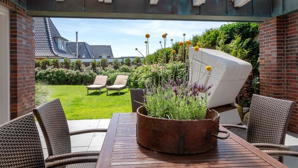 A patio with wicker furniture, a table, and a potted plant. - Strand Cottage - Ferienwohnung "strand-cottage" in Westerland (Sylt)
