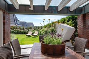 A patio with wicker furniture, a table, and a potted plant.