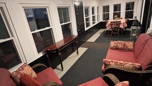 A room with a long window wall, a dining area with a table and chairs, and a seating area with sofas and a patterned rug. - Stay Now on the GOTL Strip! Across from Eddie's Grill, Steps from Multiple Bars (Geneva)