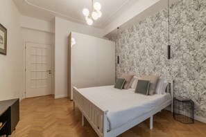 A bedroom with a bed, a wardrobe, a radiator, and a wall with a floral pattern. - Toscana 2bis - FromHometoRome (Roma)