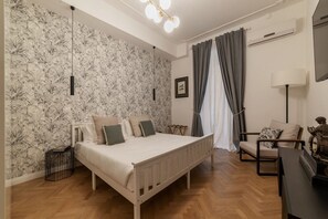 A bedroom with a bed, a chair, a lamp, and a wall with a floral pattern.