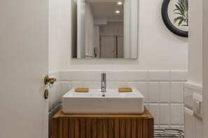 A bathroom with a white sink, wooden vanity, and a mirror.