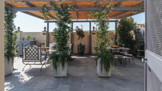 An outdoor patio with a pergola, potted plants, and outdoor seating. - Toscana 2bis - FromHometoRome (Roma)