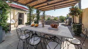 An outdoor patio with a table, chairs, and a decorative vase.