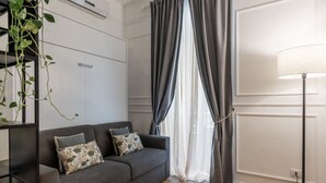 A modern living room with a grey sofa, a floor lamp, and a plant. - Toscana 2bis - FromHometoRome (Roma)
