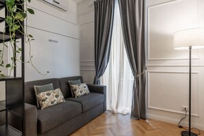 A modern living room with a grey sofa, a floor lamp, and a plant. - Toscana 2bis - FromHometoRome (Roma)