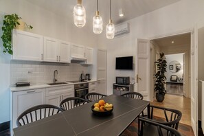 Een moderne keuken met witte kasten, een zwarte eettafel en hangende pendellampen.
