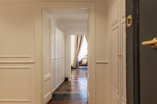 A hallway with white panel doors, a dark door on the right, and a patterned floor.