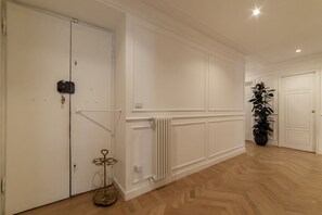 A hallway with white walls, a radiator, and a potted plant.