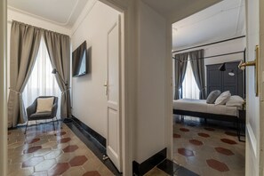 A hotel room with a bed, a chair, a TV, and a door. - Toscana 5 - FromHometoRome (Roma)
