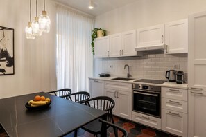 A modern kitchen with white cabinets, a black countertop, and a dining table with chairs.