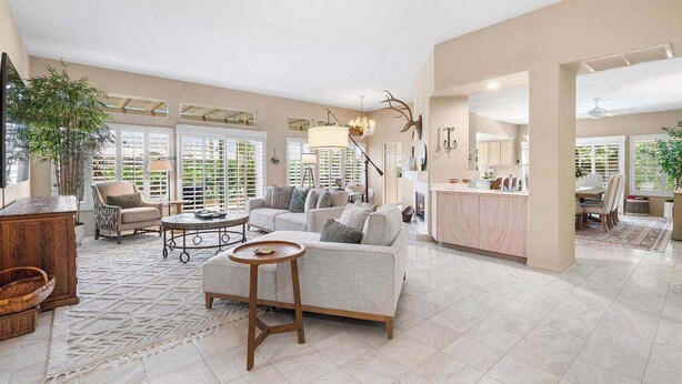 A spacious living area with a sofa, coffee table, and a dining area with chairs.