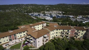 Un quartier résidentiel avec des immeubles à plusieurs étages, une marina où sont amarrés des bateaux et un paysage vallonné en arrière-plan.