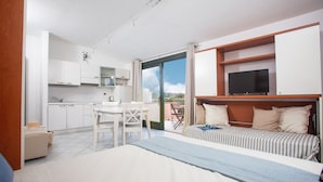 Une chambre d’hôtel moderne équipée d’un lit, d’une télévision, d’un coin repas et d’un balcon avec vue.