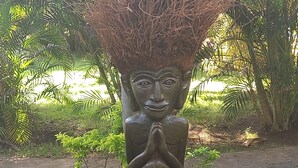 A sculpture of a seated figure with hands in a prayer position, surrounded by greenery. - Bali North Beach Villa (Kubu)