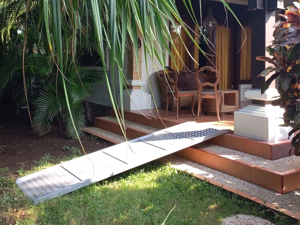A garden area with steps leading to a seating area, surrounded by lush greenery.
