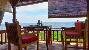 A wooden deck with a table and chairs, overlooking the sea.