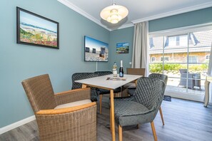 A dining area with wicker chairs, a table, and artwork on the walls.