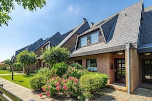 A row of modern houses with pitched roofs and brick exteriors, surrounded by well-maintained gardens and a clear sky. - Nis Puk - vacation apartment in Westerland for max. 3 persons, with west-facing terrace and (Sylt)