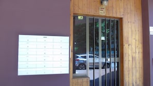 A building entrance with a wooden facade, a glass door, and a sign indicating a parking area.