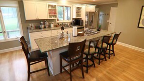 A kitchen with a central island, four bar stools, and a refrigerator. - Grand Oaks Lake House (Green Lake)