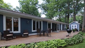 A house with a deck, outdoor seating, and a barbecue grill. - Grand Oaks Lake House (Green Lake)