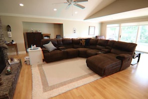 A living room with a sectional sofa, a fireplace, and a ceiling fan.