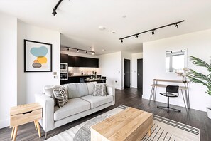 A modern living room with a sofa, coffee table, and a dining area with a chair and table. - Stunning Studio Apartment (London)