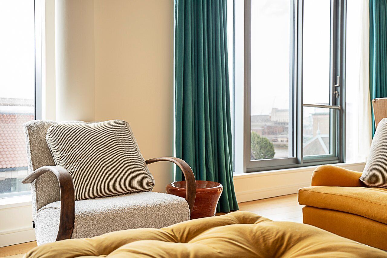 A cozy living room with a sofa, armchair, and a large window with curtains.