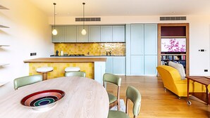 A modern kitchen with light blue cabinets, a yellow-tiled backsplash, and pendant lighting. - Luxury Penthouse Overlooking the Thames (London)