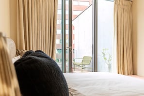 A hotel room with a bed, curtains, a window, and a view of the outside.