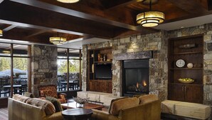 A cozy living room with stone walls, a fireplace, leather sofas, and a television.