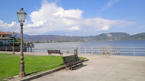 Un parc au bord de l’eau, doté de bancs et d’un lampadaire.