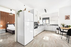 A modern kitchen with white cabinets, a refrigerator, and a dining area with a table and chairs.