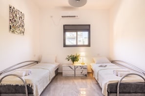 A hotel room with two beds, a marble nightstand, a lamp, and a window with a view. - Cozy 3BR Apt • Baháʼí Gardens by SeaNRent (Haifa)