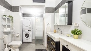 Une petite salle de bain comprenant des toilettes, un lave-linge, un lavabo et un miroir.