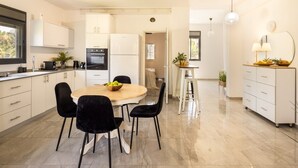 Une cuisine moderne avec un coin repas, des meubles blancs et une table ronde avec des chaises.