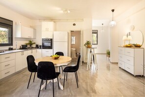 A modern kitchen with a dining area, white cabinetry, and a round table with chairs.