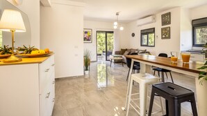 A modern kitchen with a dining area, a bar, and a living space with a sofa and a coffee table.