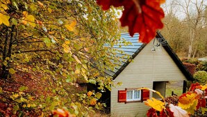 Een klein huis met een puntige dakschildering, omgeven door herfstbladeren.