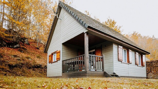 Ein eingeschossiges Haus mit Veranda, umgeben von Herbstlaub.
