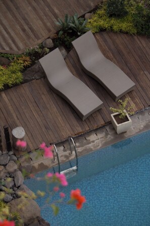 A poolside area with two lounge chairs, a wooden deck, and a small pool. - Parigata Resorts Jimbaran (Jimbaran)
