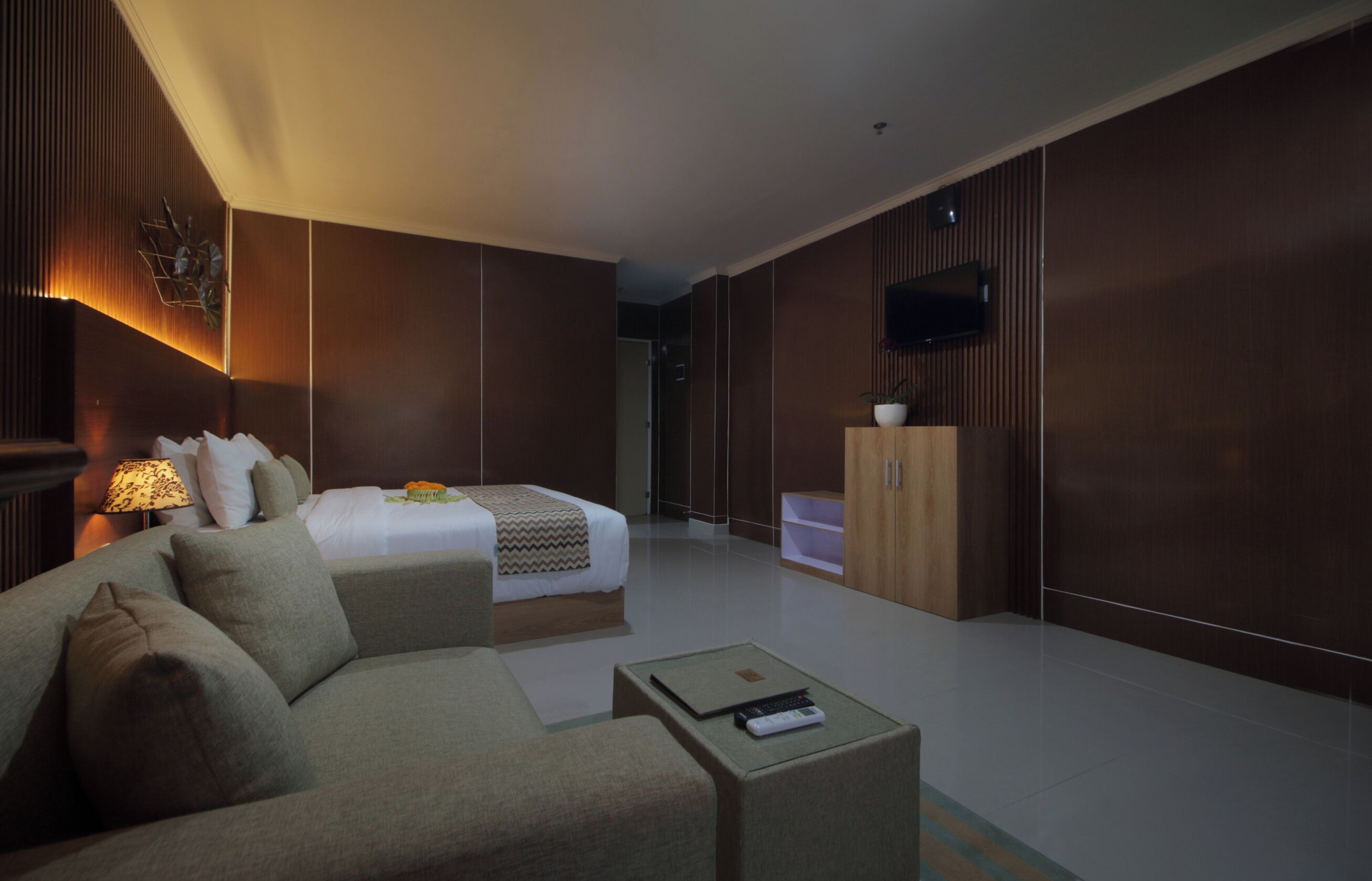 Una habitación de hotel moderna con cama, sofá, televisión y un armario.