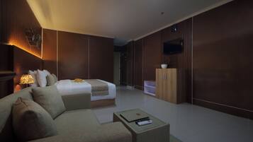 Una habitación de hotel moderna con cama, sofá, televisión y un armario.
