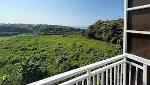A balcony with a view of a lush green landscape and a distant town. - Parigata Resorts Jimbaran (Jimbaran)
