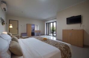 A hotel room with a bed, a desk, a television, and a view of the outdoors. - Parigata Resorts Jimbaran (Jimbaran)