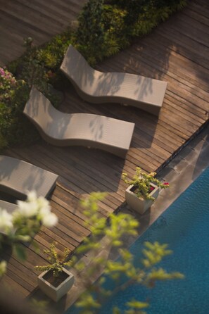 Una terraza de madera con sillones de descanso y macetas.