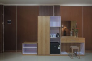 A modern bedroom with a wooden wardrobe, a desk with a mirror, and a small stool. - Parigata Resorts Jimbaran (Jimbaran)
