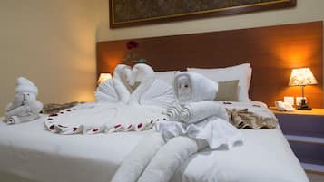 A hotel room with a neatly made bed, a bedside lamp, a telephone, and a painting on the wall.